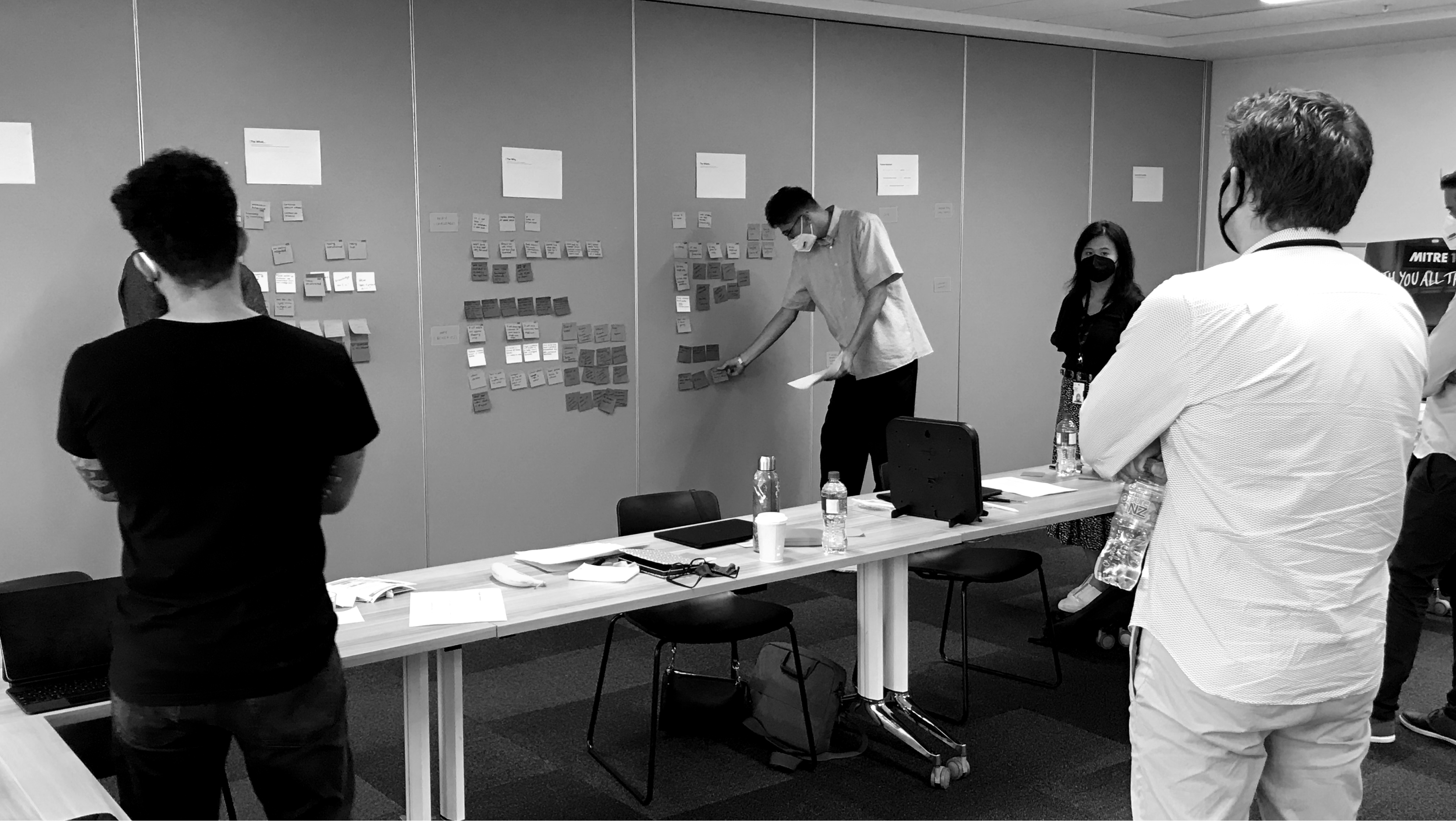 Workshop participants mapping who, what, where and why on a wall of sticky notes